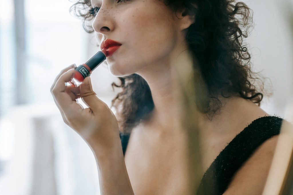 Image showing woman putting on lipstick, image portrays a happy woman after lip fillers.